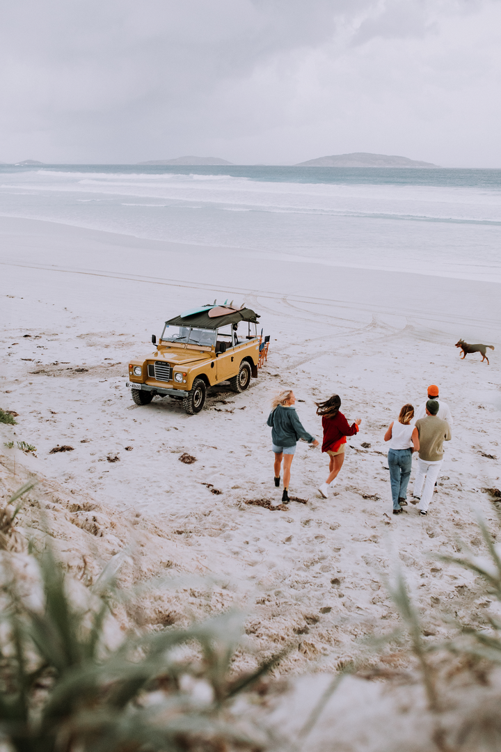 Picture of a car on the beach with people around it